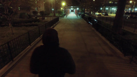 man in hoodie walking in street at night in New York City NYC