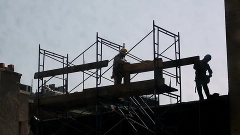 construction workers taking a break at site - silhouettes of men in hardhats on scaffolding at top of building in NYC