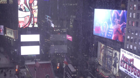 panning across window view looking down on Times Square in winter - taxis in traffic - snowing 4K and 1080 HD in NYC