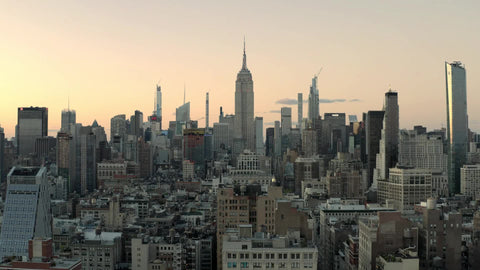 Empire State Building in early evening day aerial flying over buildings Manhattan New York City NYC