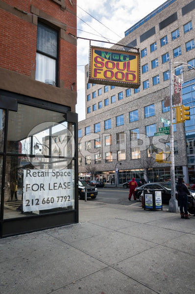 Harlem soul food restaurant with retail space for lease sign on corner - Uptown Manhattan during day