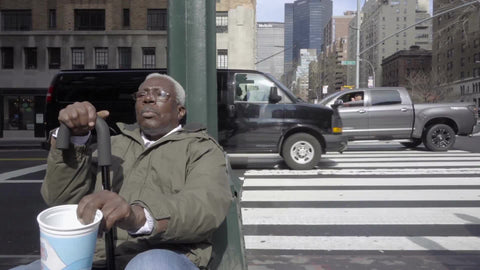 homeless black man with cane sitting on Park Ave corner shaking cup for help in 1080 HD in NYC