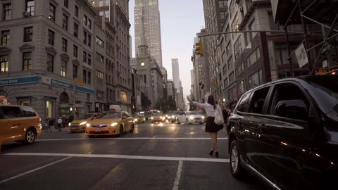 woman haling cab on 5th ave in early evening with Empire State Building lights and cars driving in rush hour traffic in summer nightlife in 4K and 1080 HD NYC