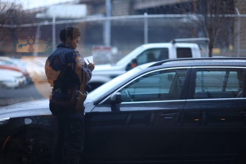 female police officer writing ticket on car windshield - NYPD cop giving summons