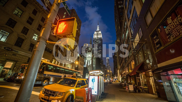 Empire State Building at night on 5th Avenue with taxicab parked on corner in Manhattan