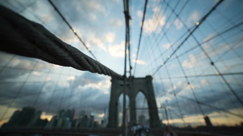 close-up of suspension rope on Brooklyn Bridge with sunset and tourists out of focus in NYC