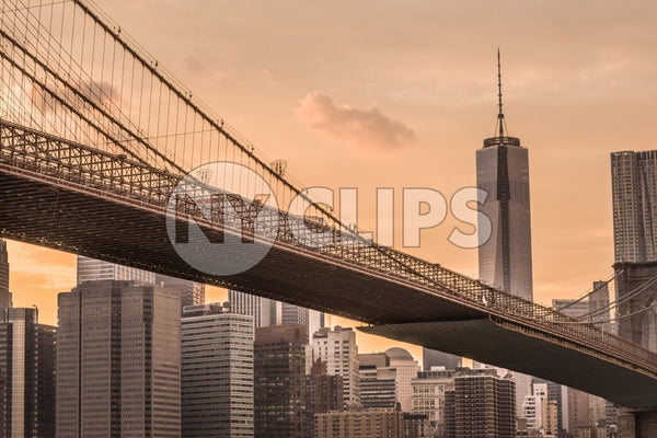 Freedom Tower from across Brooklyn Bridge at sunset with beautiful orange sky in NYC