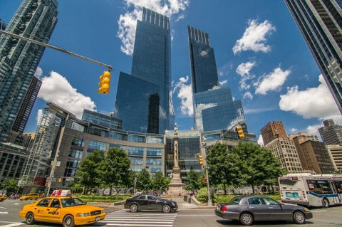 Time Warner Towers at Columbus Circle during day, blue sky in summer with cars and taxi cab driving around circular street