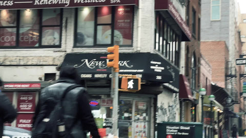 two friends crossing the street on cold winter day with New York sign by Houston Street subway train station entrance Downtown Manhattan New York City NYC