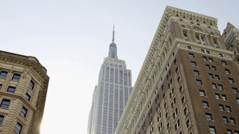 Empire State Building from upward angle street view - tilting down to Herald Square and 34th street in Manhattan on summer day in NYC
