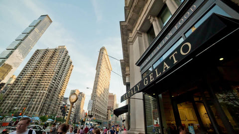 Eataly Gelato restaurant in Flatiron District with skyscraper and 5th ave clock on summer day in NYC