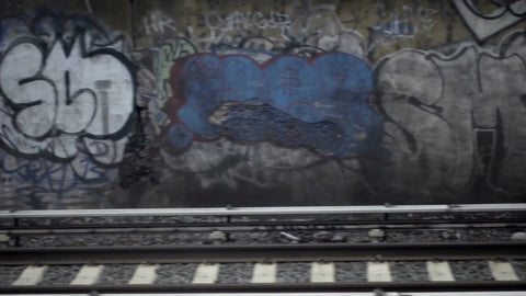 graffiti on wall passing from subway view over tracks - gritty dirty beautiful urban art in Brooklyn in 1080 HD NYC