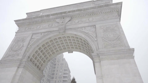 arch at Washington Square Park tilting to Christmas tree snowing on winter blizzard day in NYC
