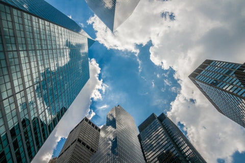 corporate office buildings - upward angle of glass window skyscrapers over blue sky on sunny summer day in Manhattan