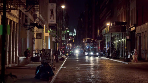 quiet cobblestone street in SoHo at night with Chrysler Building in background - two people crossing