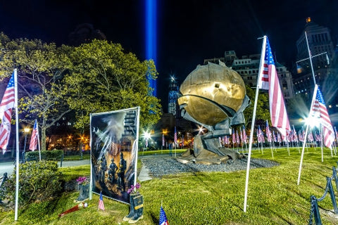 September 11th memorial painting of firefighters - heroes commemorated in Battery Park at night with American flags and 911 beams
