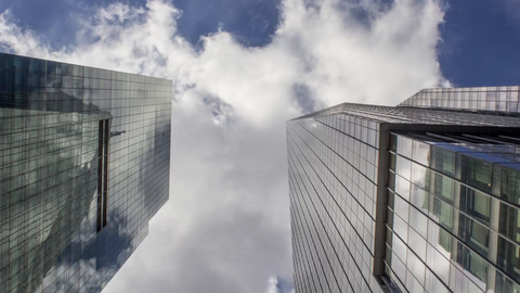 upward angle of two skyscrapers in Midtown Manhattan during the day - 4k timelapse of blue sky with clouds floating overhead