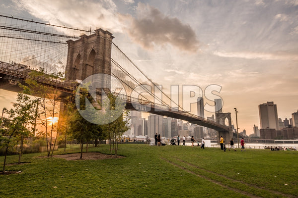 Brooklyn Bridge Park with people enjoying sunset with Manhattan skyline across East River in NYC summer