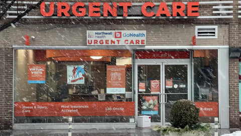 car driving past Urgent Care clinic with large sign in snow storm snowing blizzard cold winter New York City NYC