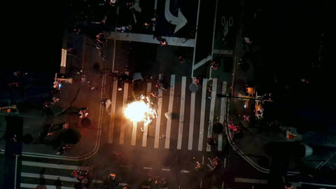 man lighting garbage can on fire in street at night