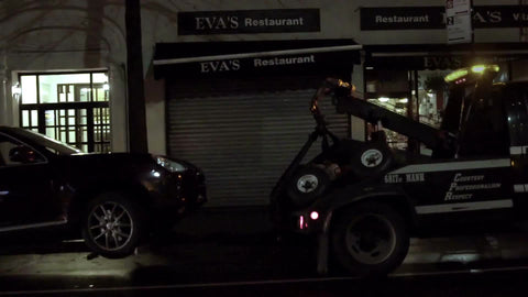 NYPD tow truck towing parked car at night