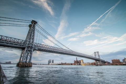 Williamsburg Bridge in Brooklyn in late afternoon during day with East River water and blue sky