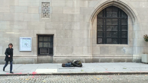 people ignoring, walking by homeless man sleeping on street in front of church in the cold in New York City