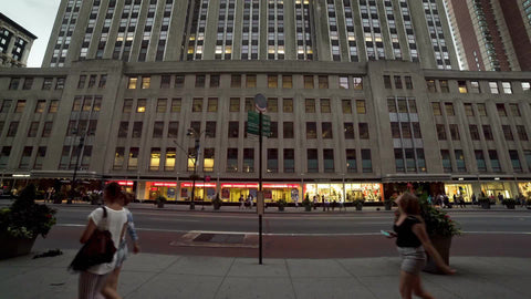 tilting up to Empire State Building from street view, people looking up at towering skyscraper on summer day in Manhattan NYC