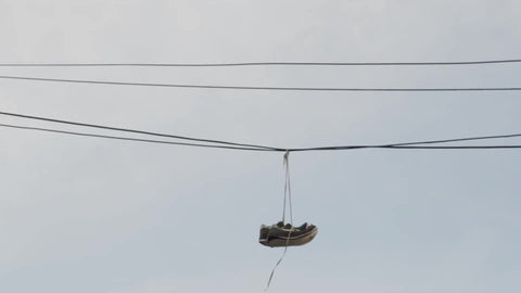 sneakers hanging from power lines - shoe tossing in urban area