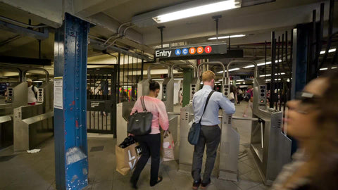 subway turnstiles on summer day interior - people entering turnstile inside train station in NYC