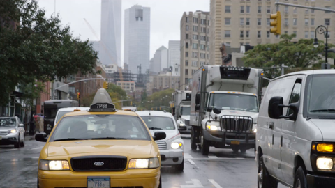 taxi cab driving in rain on wet road - 6th Ave with Freedom Tower in background in Manhattan NYC
