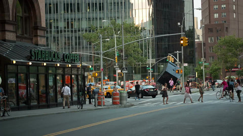 Starbucks Coffee House and famous cube sculpture on Cooper Square in Greenwich Village in summer during day, taxicab turning corner, Manhattan NYC