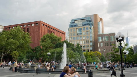 friends hugging in Washington Square Park on summer day with water sprinkler in NYC
