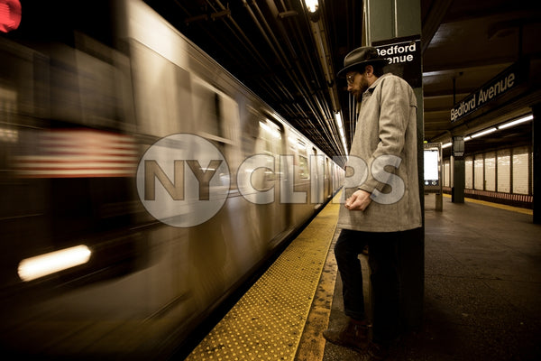 man leaning on column in Bedford Ave subway station New York City