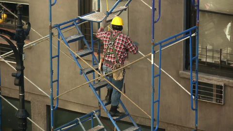 construction worker in hardhat climbing scaffolding on building in NYC