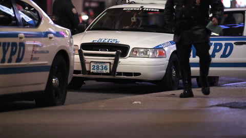 NYPD officers getting in police cars and driving away at night