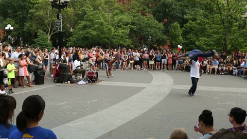 acrobats performing in Washington Square Park before a crowd - airplane spin on head on summer day in NYC