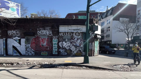 bicycle shop parked car stuck on pile of snow driving through West Village in winter with graffiti on brick buildings Manhattan New York City NYC