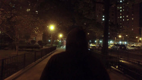 unidentified man in black hoodie walking alone at night in projects in NYC