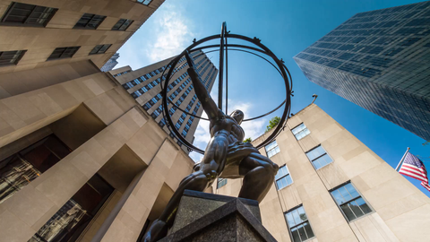 upward angle of famous Atlas statue outside Rockefeller Center with American flag - timelapse in 4K and 1080 HD NYC