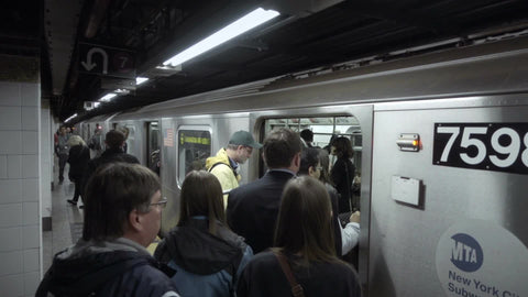 crowded platform of New Yorkers people boarding busy MTA subway car man in Yankee All Star Game jacket in slow motion
