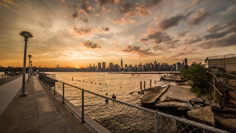 Manhattan skyline with gritty view of junk and broken down garbage in Brooklyn across East River at sunset