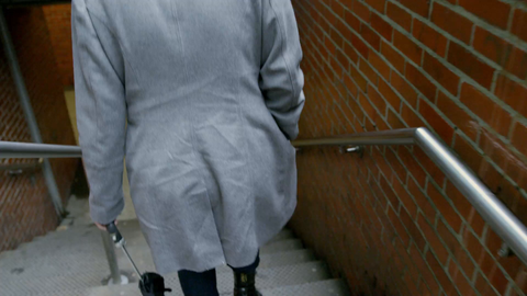 woman walking downstairs in subway station in coat and hat on cold winter day - 4K slow motion in NYC