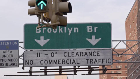 close up Brooklyn Bridge sign, clearance no commercial traffic, passing underneath, green light overhead in NYC