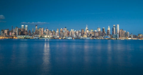Manhattan skyline from across East River early evening with blue sky and water