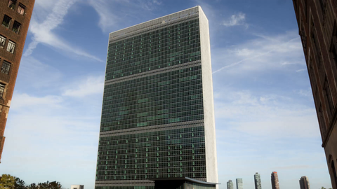 full shot of UN building in Midtown Manhattan flanked between two buildings - 4K timelapse during the day with blue sky