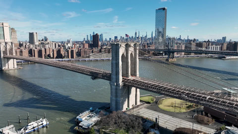 aerial approaching American flag on Brooklyn Bridge East River Manhattan skyline New York City