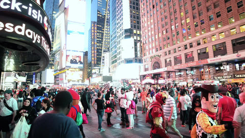 Times Square at night with performers in costumes on crowded street