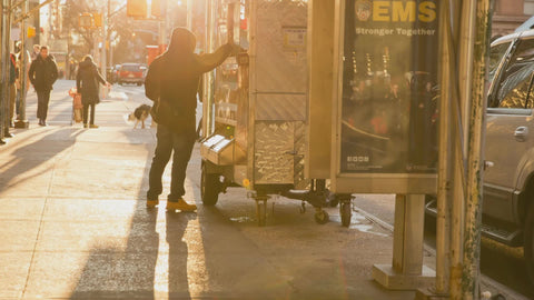 man taking food bag at street vendor food cart in early morning NYC