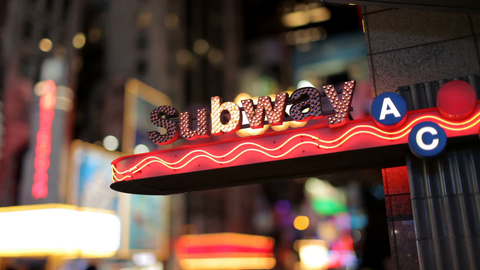 bright subway sign lights blinking near Times Square at night in New York City